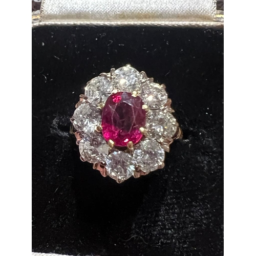 331 - An Edwardian style ruby and diamond cluster ring, the oval cut ruby within surround of eight round c... 