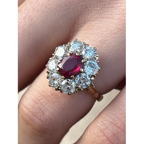 331 - An Edwardian style ruby and diamond cluster ring, the oval cut ruby within surround of eight round c... 