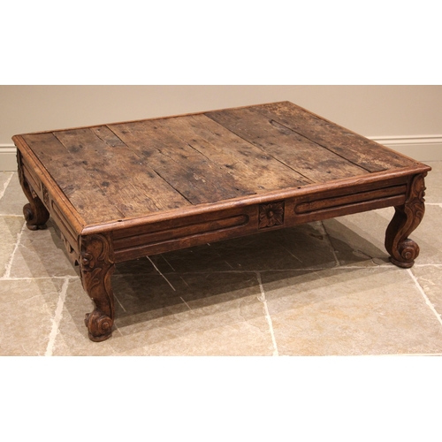 1081 - A rustic Indian hardwood coffee table, the plank top above a channelled frieze and heavy carved cabr... 