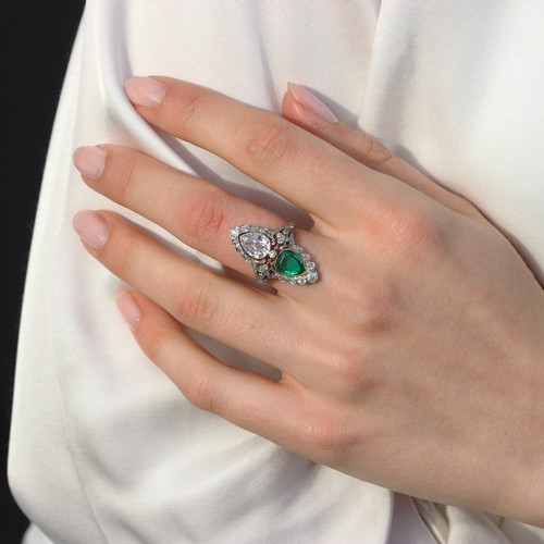 339 - A ‘Belle Epoque’ emerald and diamond set ring, the old cut pear cut diamond within white metal milgr... 