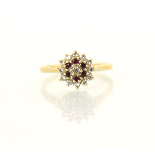 111 - An untested ruby and diamond set cluster ring, the central round cut diamond within a surround of si... 