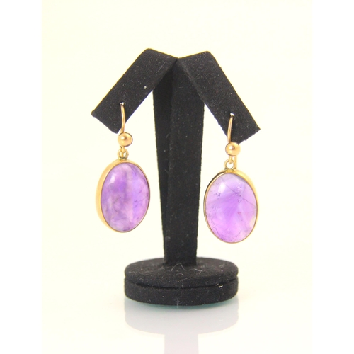137 - A pair of amethyst earrings, the oval cabochons within yellow metal rob over mount, with shepherd ho... 