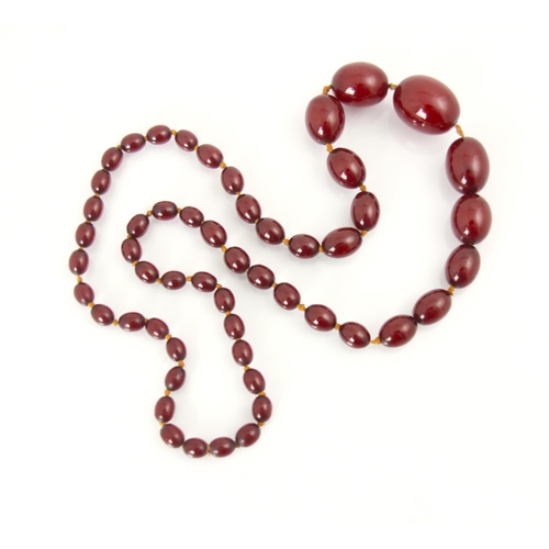 141 - A string of cherry coloured 'amber' beads, the fifty two graduated barrel shaped beads upon string, ... 