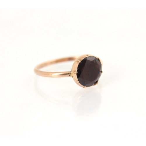 147 - A 19th century style garnet ring, the circular flat cut garnet (possibly foiled back) in rose gold c... 