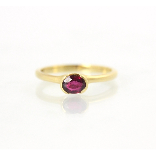 148 - A bespoke 18ct yellow gold untested ruby solitaire ring, the oval cut stone within a cut out raised ... 