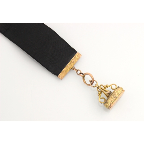 153 - An early 20th century yellow metal mounted fob watch/seal fob strap, the black silk ribbon with engr... 