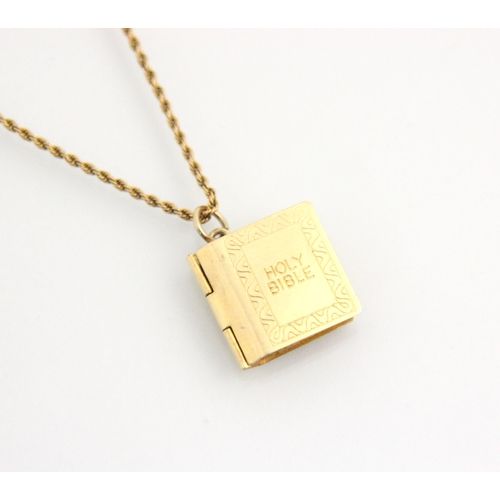 155 - A 9ct yellow gold pendant, the realistically modelled bible with engraved detail, opening to reveal ... 