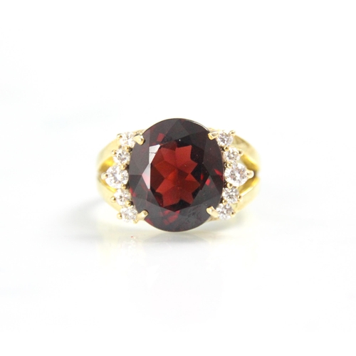 167 - A garnet and diamond dress ring, the oval cut garnet with five round cut diamonds to each side, with... 