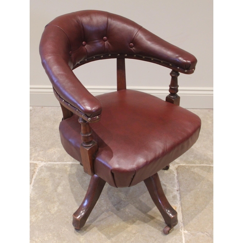 836 - A walnut revolving desk chair, early 20th century, later re-covered in ox-blood red leather, the arc... 