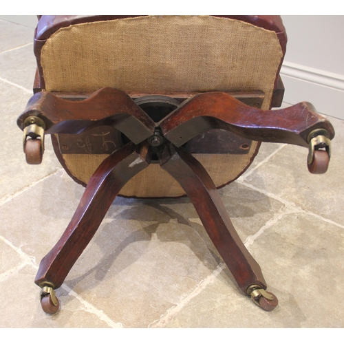 836 - A walnut revolving desk chair, early 20th century, later re-covered in ox-blood red leather, the arc... 