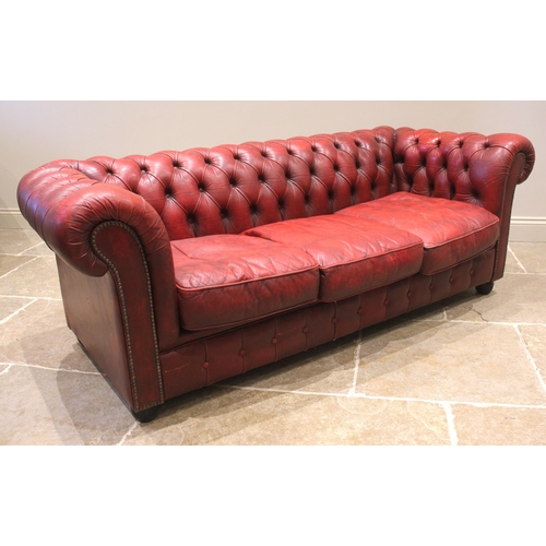 856 - A red leather Chesterfield sofa, late 20th century, of deep set button back form, enclosing three lo... 