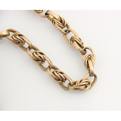 94 - An early 20th century yellow metal watch chain, the triple interlocking oval links suspending two lo... 