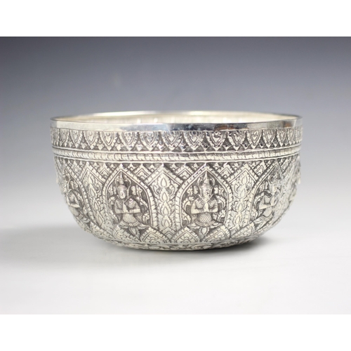 47 - A Burmese silver coloured bowl, the ten repeating embossed panels depicting deities among repeating ... 