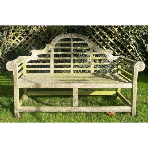 866 - A Lutyens hardwood slatted garden bench, of typical construction, with an arched back rest upon legs... 