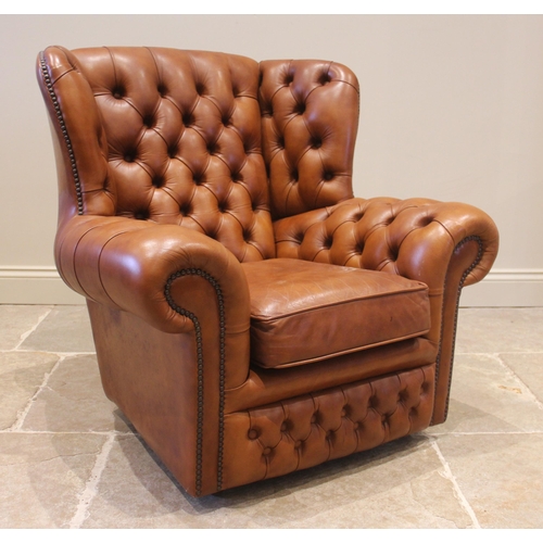 858 - A tan leather wing back sofa and conforming armchair, both with a button back extending to shaped wi... 