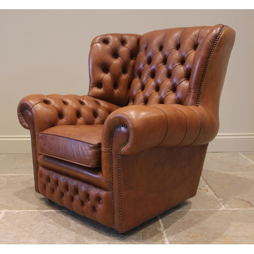 858 - A tan leather wing back sofa and conforming armchair, both with a button back extending to shaped wi... 