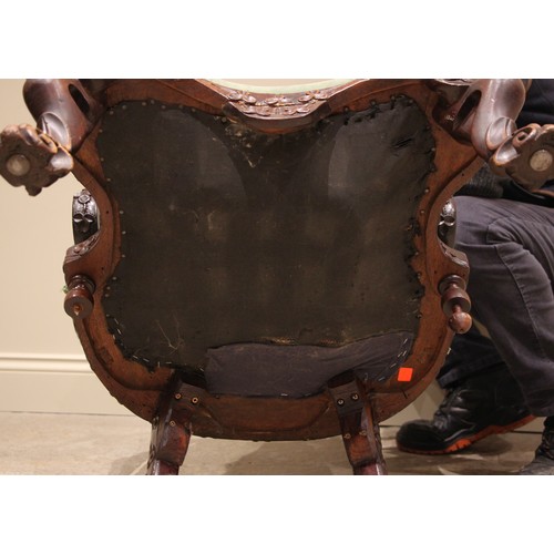 810A - A Ceylonese carved wood and upholstered armchair, 19th century, the arched frame profusely carved wi... 