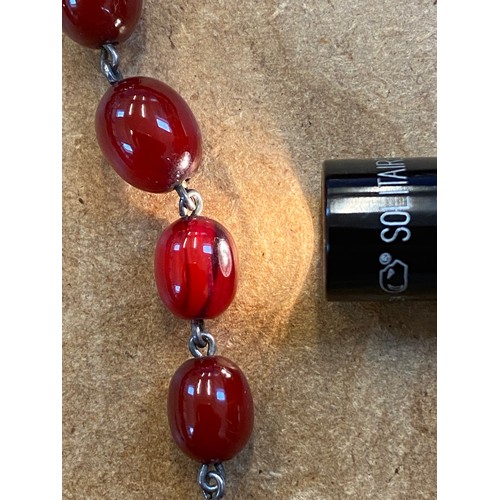 79 - A string of cherry coloured 'amber' beads, the forty two graduated polished oval beads with base met... 