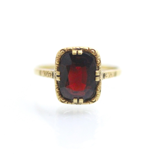 132 - A 19th century style untested garnet ring, the central cushion cut stone within yellow metal carved ... 