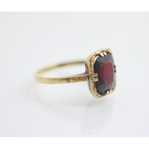 132 - A 19th century style untested garnet ring, the central cushion cut stone within yellow metal carved ... 