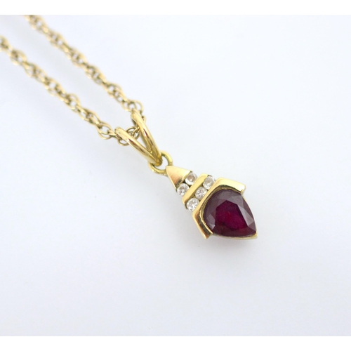 133 - An untested ruby and diamond pendant, the pear cut red stone within yellow metal mount surmounted by... 