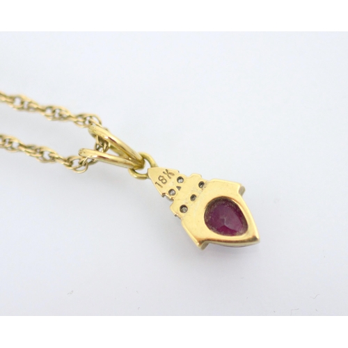 133 - An untested ruby and diamond pendant, the pear cut red stone within yellow metal mount surmounted by... 