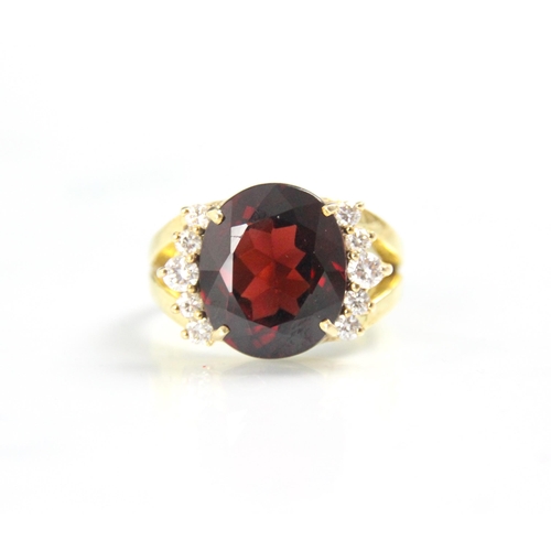 170 - A garnet and diamond dress ring, the oval cut garnet with five round cut diamonds to each side, with... 