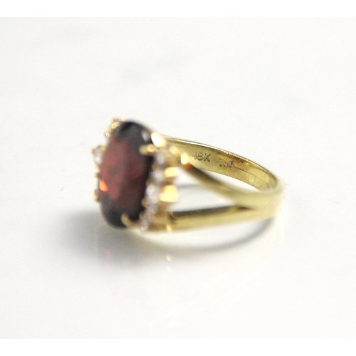 170 - A garnet and diamond dress ring, the oval cut garnet with five round cut diamonds to each side, with... 