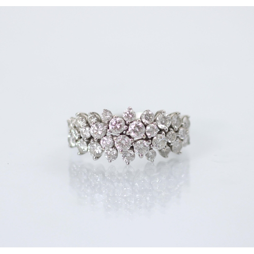 193 - A stylised diamond cluster ring, the graduated round cut diamonds set within a raised claw set mount... 