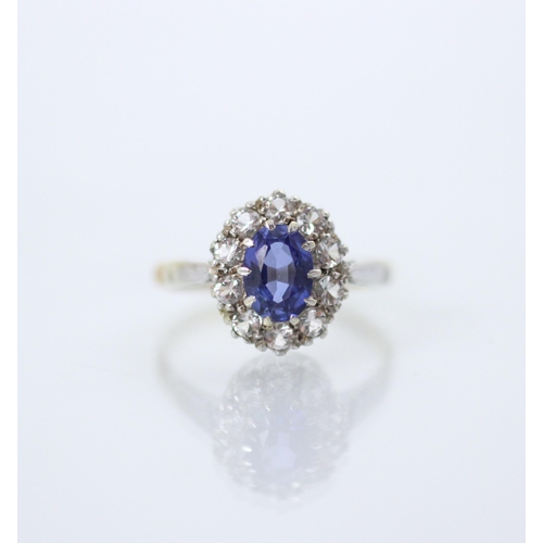 215 - An Edwardian style synthetic sapphire cluster ring, the oval cut blue stone within surround of ten w... 