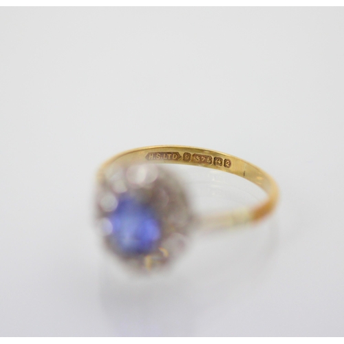 215 - An Edwardian style synthetic sapphire cluster ring, the oval cut blue stone within surround of ten w... 