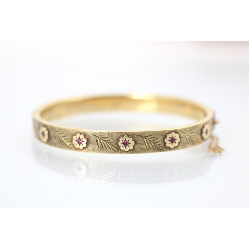 223 - A Cropp and Farr 9ct yellow gold bangle, the hollow bangle set with five synthetic rubies within flo... 