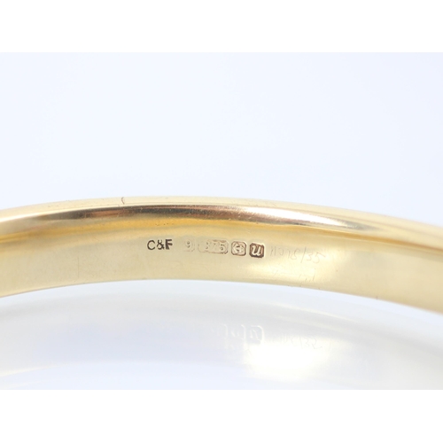 223 - A Cropp and Farr 9ct yellow gold bangle, the hollow bangle set with five synthetic rubies within flo... 