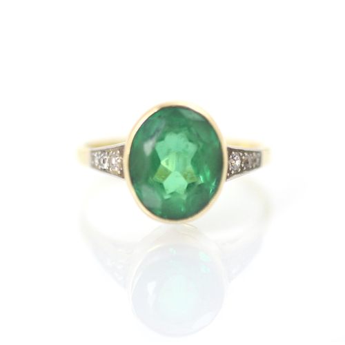 235 - An early 20th century green paste and diamond set ring, the oval cut green stone within white metal ... 