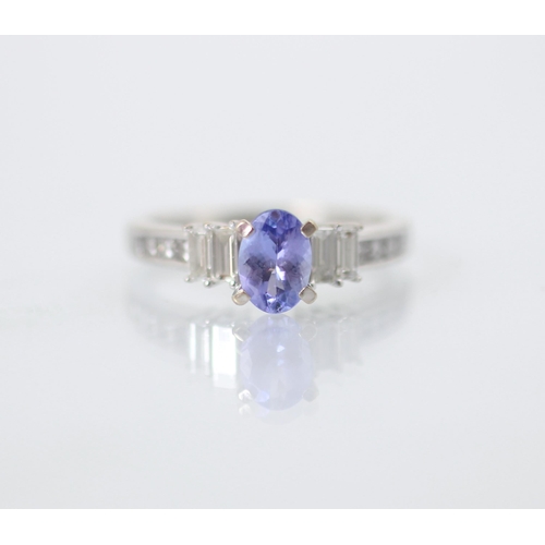 240 - A diamond and untested tanzanite ring, the oval cut centre stone with two graduated baguette cut dia... 