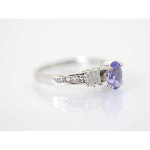 240 - A diamond and untested tanzanite ring, the oval cut centre stone with two graduated baguette cut dia... 