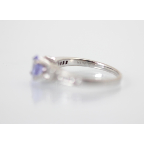 240 - A diamond and untested tanzanite ring, the oval cut centre stone with two graduated baguette cut dia... 