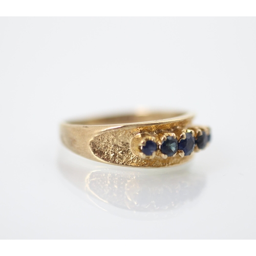 243 - A 9ct yellow gold and untested sapphire dress ring, the five graduated round cut blue stones raised ... 