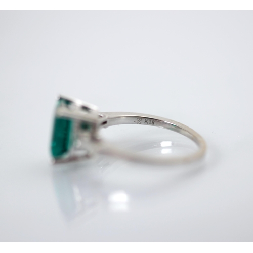 244 - A synthetic emerald and diamond set ring, the emerald cut synthetic emerald set with white metal cla... 