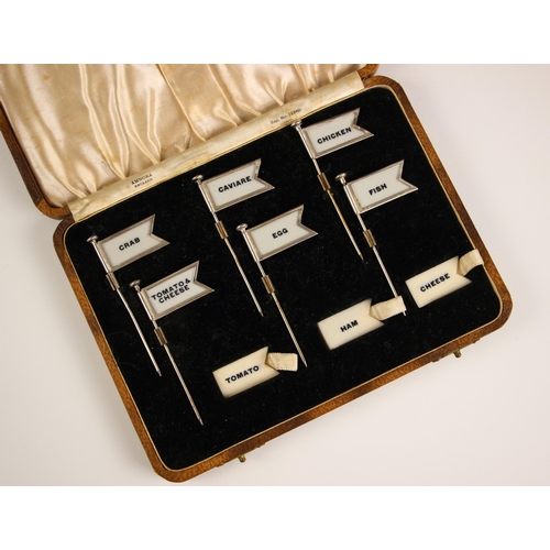 69 - A cased set of six sterling silver sandwich flags or labels by Amnora, early 20th century, the six f... 