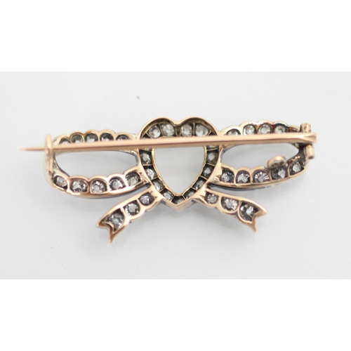 256 - An early 20th century diamond heart brooch, the central heart motif within an openwork bow, set thro... 