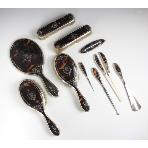 94 - A George V silver and tortoiseshell mounted dressing table set, comprising two hair brushes, a mirro... 