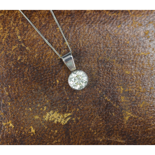 130 - A diamond solitaire pendant, the round cut diamond set within a white metal rub over mount, with pla... 