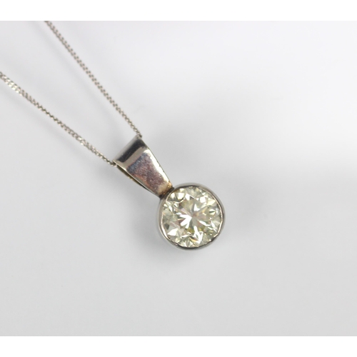 130 - A diamond solitaire pendant, the round cut diamond set within a white metal rub over mount, with pla... 