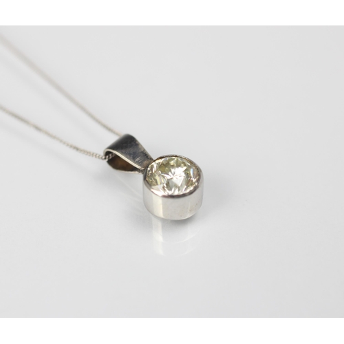 130 - A diamond solitaire pendant, the round cut diamond set within a white metal rub over mount, with pla... 