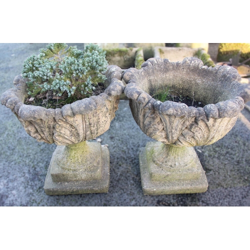 872 - A pair of reconstituted leaf moulded urn planters, each raised upon an integral stepped plinth base,... 