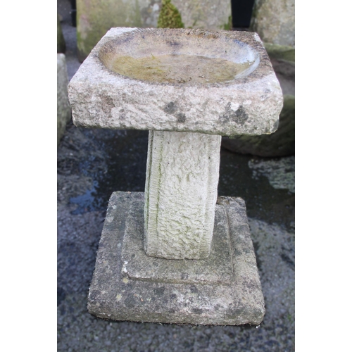 878 - A reconstituted stone bird bath, the square top with a shallow circular well upon a pedestal of tape... 