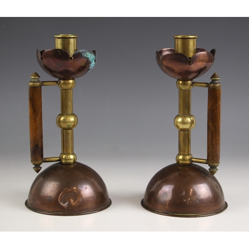 654 - A pair of Arts & Crafts style copper and brass chamber sticks in the manner of Christopher Dresser, ... 