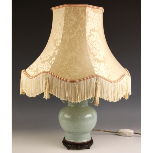 686 - A Chinese porcelain celadon lamp base, with all over scrolling leaf and vine decoration, hardwood ba... 