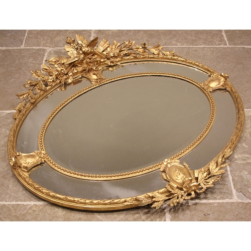 702 - A 19th century giltwood and gesso oval wall mirror, surmounted with a pair of birds, quiver of arrow... 